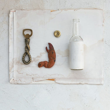 Wine bottle, bottle opener, and bar accessories arranged on a light marble surface