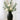 Charcoal ceramic tall vase with matte finish, styled with ivory ranunculus and eucalyptus stems on a light wood table.
