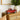 Vintage-style red metal truck decor on a wooden cabinet, styled next to a cream ceramic vase with greenery in a cozy living space.