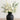 Charcoal ceramic vase with soft matte texture, filled with ivory roses, ranunculus, eucalyptus, and white hydrangea on a neutral tabletop.