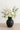 Charcoal ceramic vase with soft matte texture, filled with ivory roses, ranunculus, eucalyptus, and white hydrangea on a neutral tabletop.