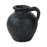 A rustic black ceramic pitcher shaped vase with a rounded body, short flared rim, and a single loop handle, shown on a plain white background.