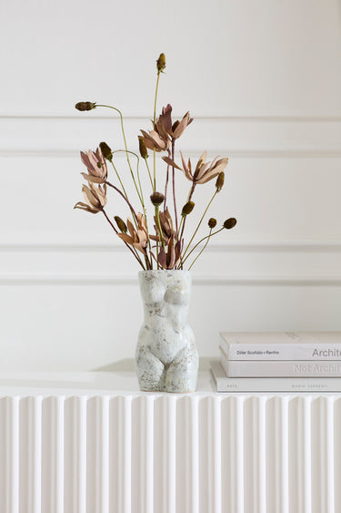 Sculptural ceramic female form vase styled with dried flowers on a white console