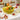 Glossy yellow ceramic banana fruit bowl with dimensional banana details, styled as a colorful kitchen centerpiece with fresh fruit and florals.