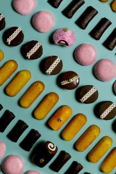 Assorted chocolates including pink, yellow, and brown on a blue background