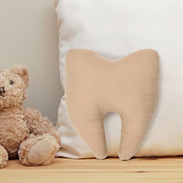 Tan cotton tooth fairy pillow styled on a bed with a white cushion and teddy bear.