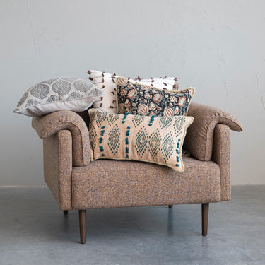 Brown armchair with patterned cushions against a gray wall