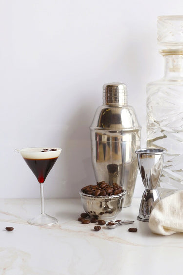 Cody Foster Espresso Martini Ornament paired with a shaker and coffee beans. 