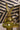 Gold rabbit figurine with a mustache on a stand with flowers against a striped background