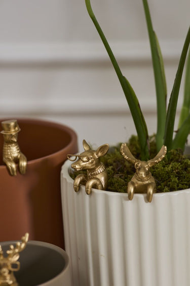 Antique gold deer and fox pot huggers styled on a white planter with moss and greenery