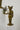 Bronze statue of a cat in a suit with a tray holding candles and flowers on a white pedestal.