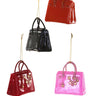 Cody Foster Luxury Bag Ornament Set featuring four glossy glass handbag ornaments in black, pink, red, and orange with hanging cords.