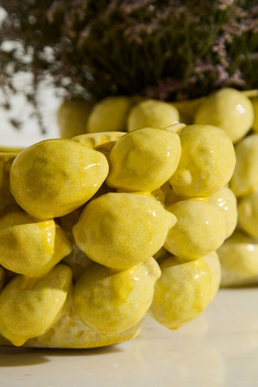 Yellow ceramic layered lemon planter pot with dimensional hand-applied lemon details, matte reactive glaze, and floral arrangement styling for bright kitchen or home decor.