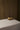Antique gold metal Totem Pumpkin displayed on a neutral linen-covered table against a dark brown backdrop.