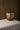 Large gold metal totem pumpkin with black curved stem on linen-covered table