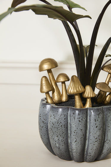 Whimsical gold mushroom plant stakes displayed in a textured gray ceramic planter